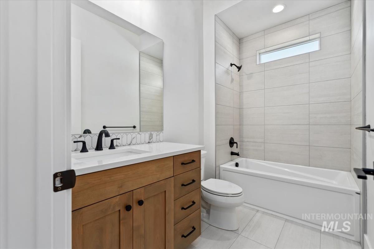 Full bath featuring vanity, shower / bathtub combination, and light tile patterned floors