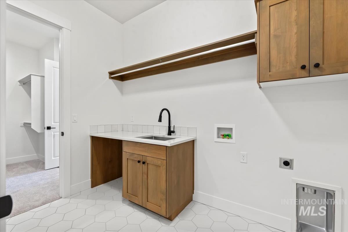 Washroom featuring hookup for a washing machine, cabinet space, light colored carpet, hookup for an electric dryer, and light tile patterned floors