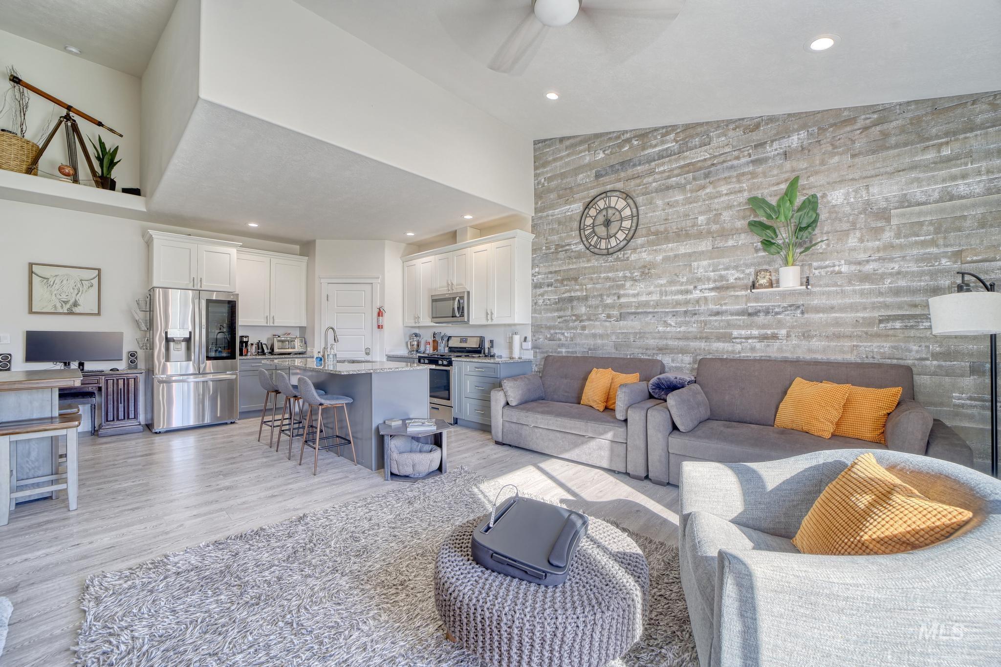 Living area featuring light wood finished floors, recessed lighting, high vaulted ceiling, and a ceiling fan