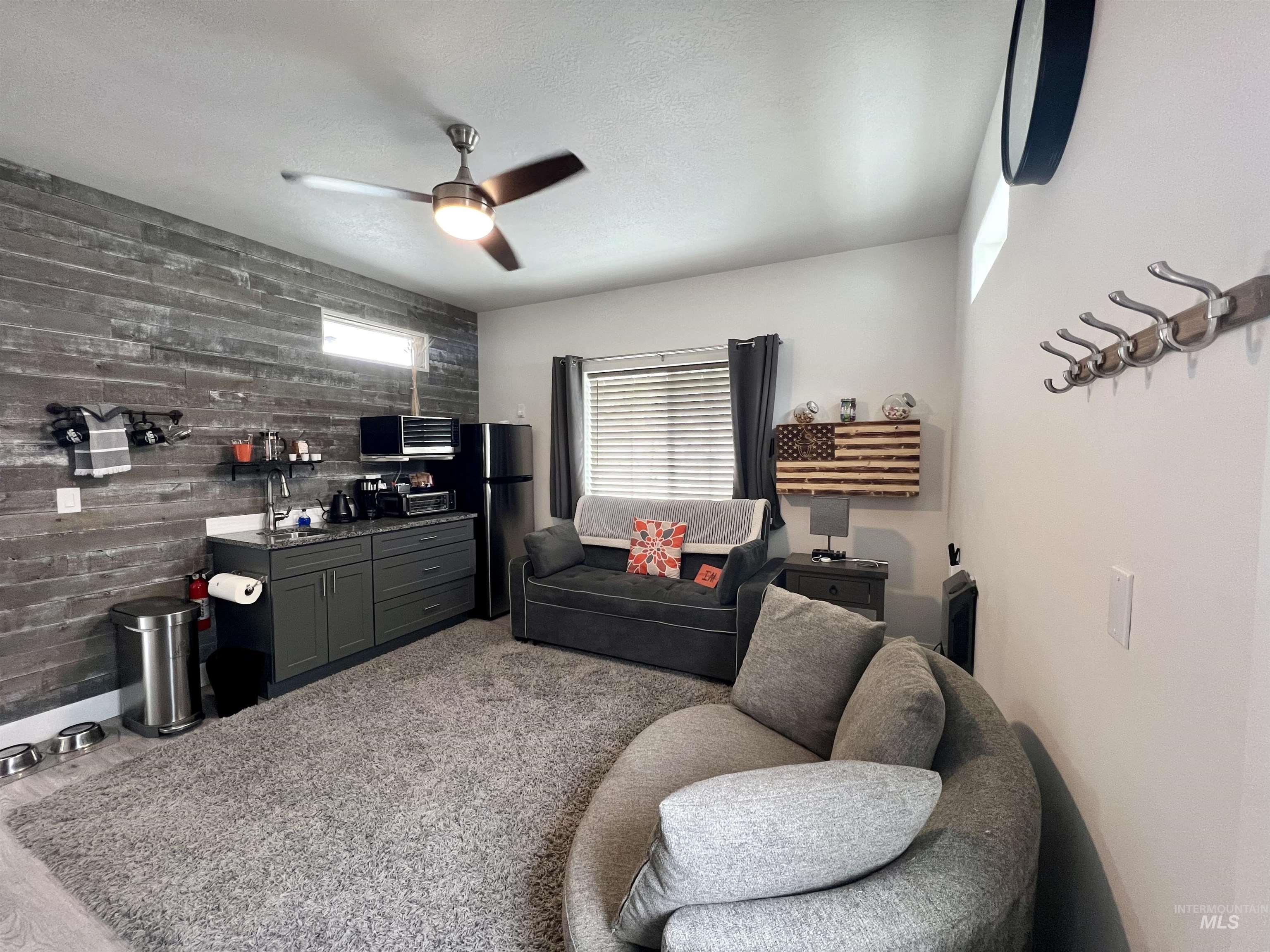 Living room with wood walls, a textured ceiling, an accent wall, and a ceiling fan