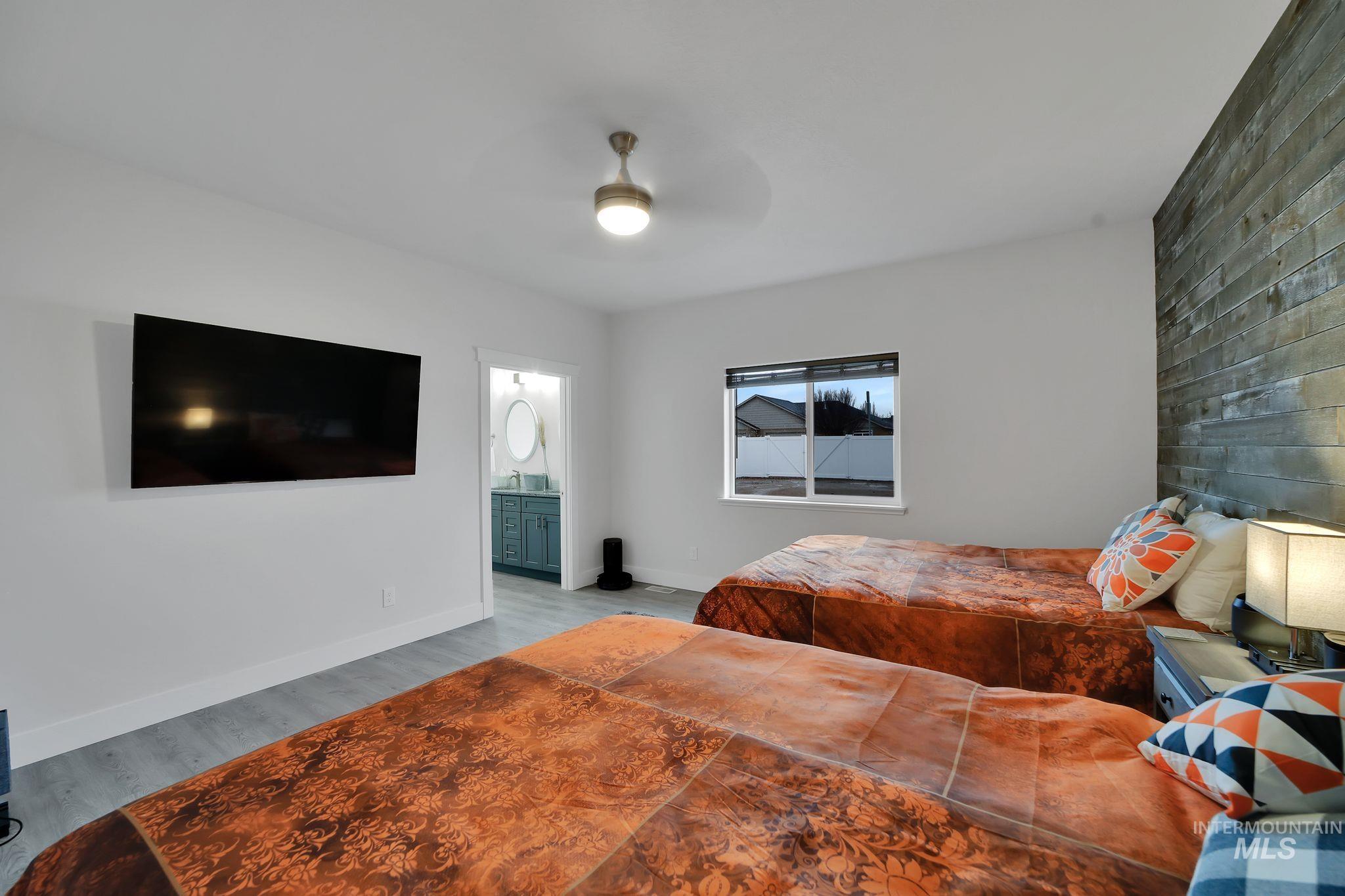 Bedroom with wood finished floors, a ceiling fan, and ensuite bathroom