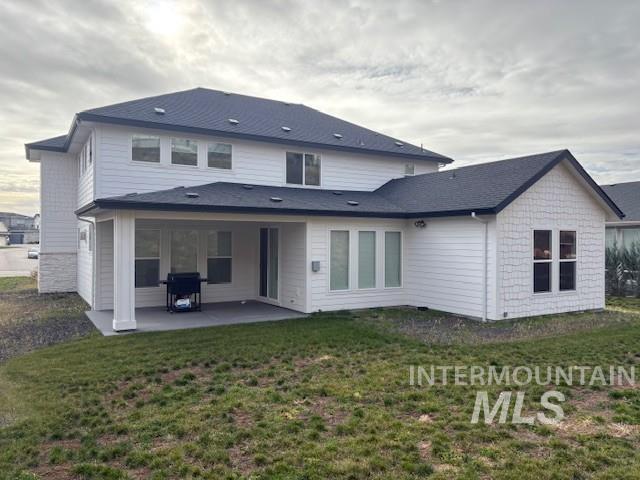 Rear view of property with a lawn and a patio