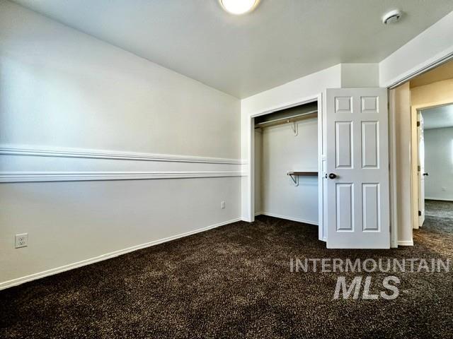 Unfurnished bedroom featuring dark colored carpet and a closet