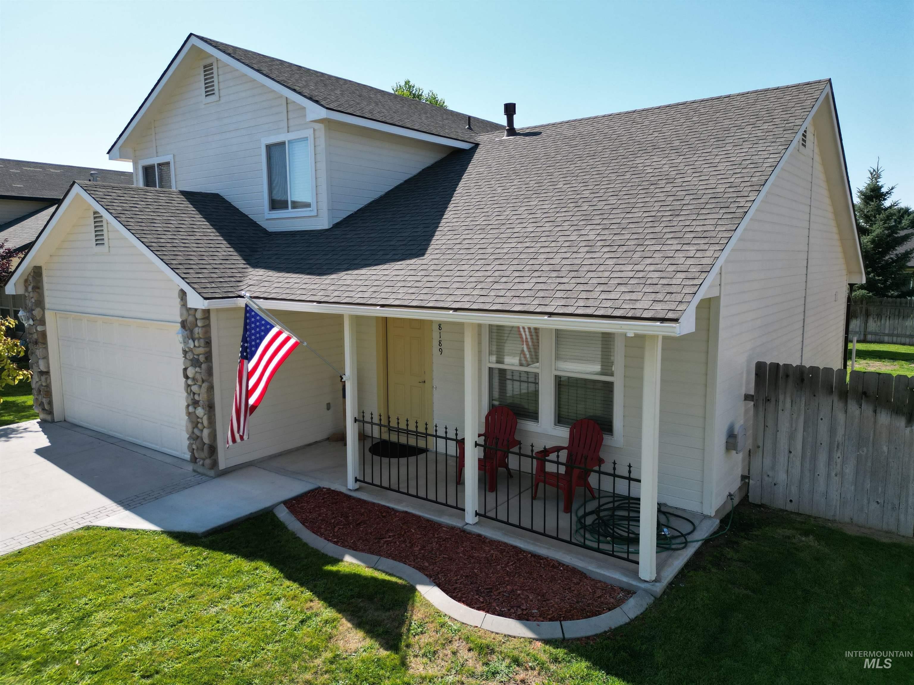 View of front of property featuring roof with shingles, an attached garage, covered porch, concrete driveway, and stone siding