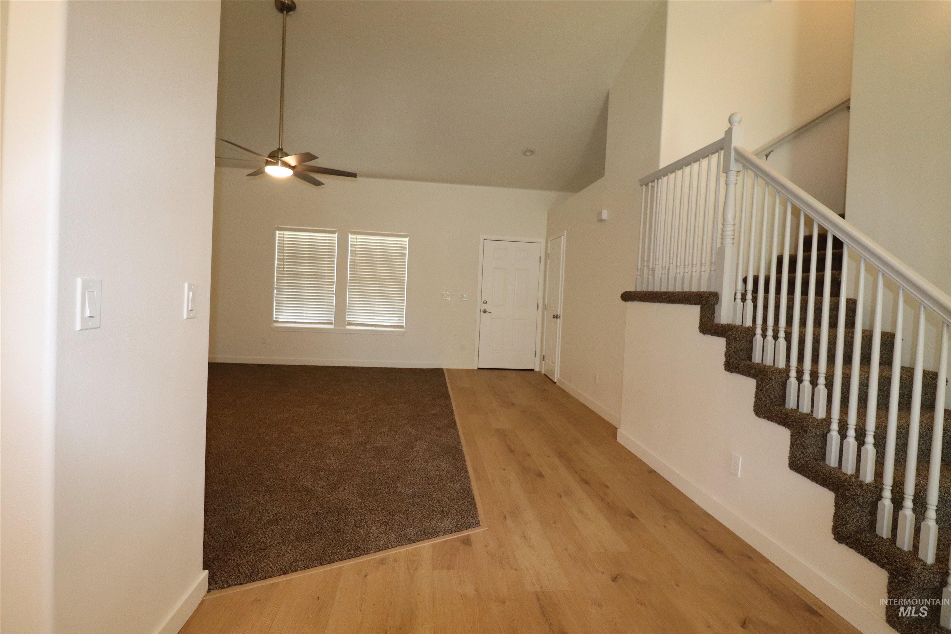 Entryway featuring ceiling fan, wood finished floors, high vaulted ceiling, and stairs