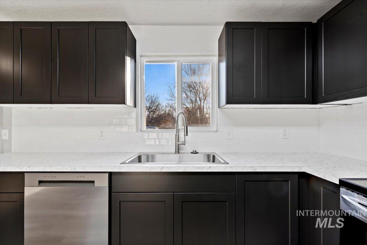 Kitchen featuring dishwasher, light countertops, and dark cabinetry