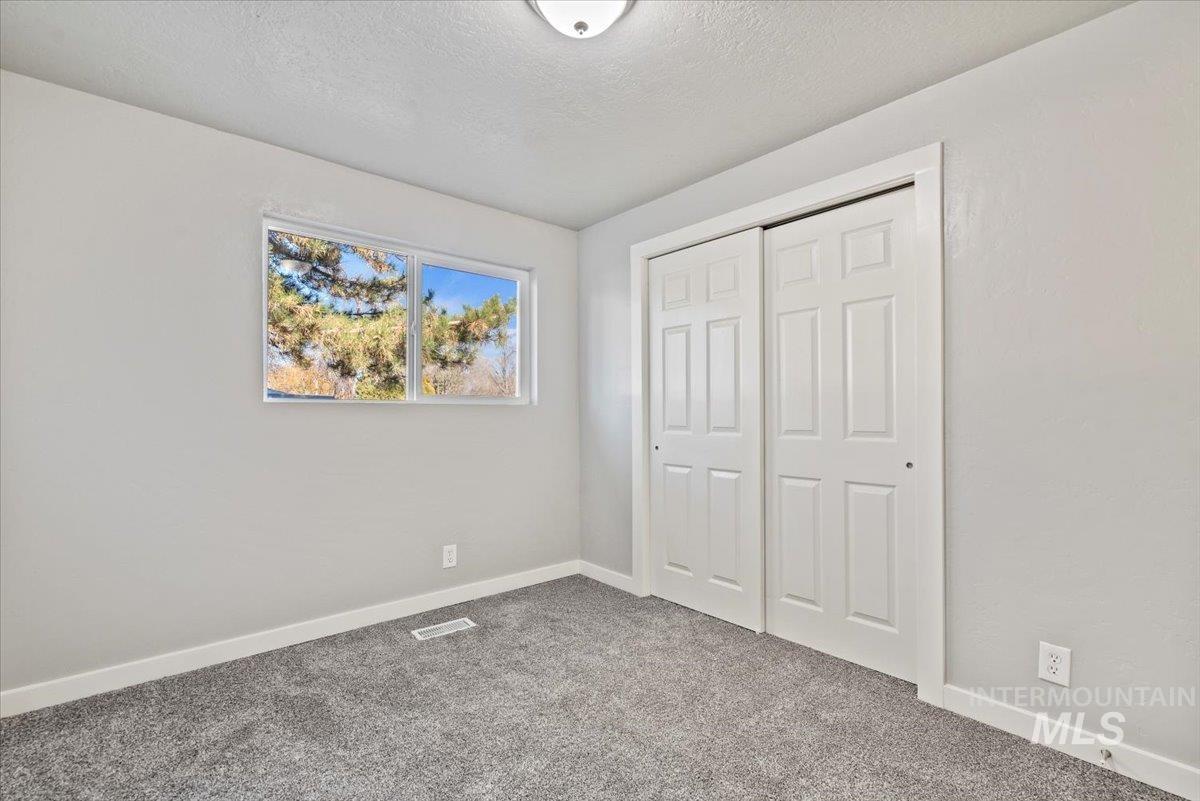 Unfurnished bedroom featuring carpet flooring, a textured ceiling, and a closet