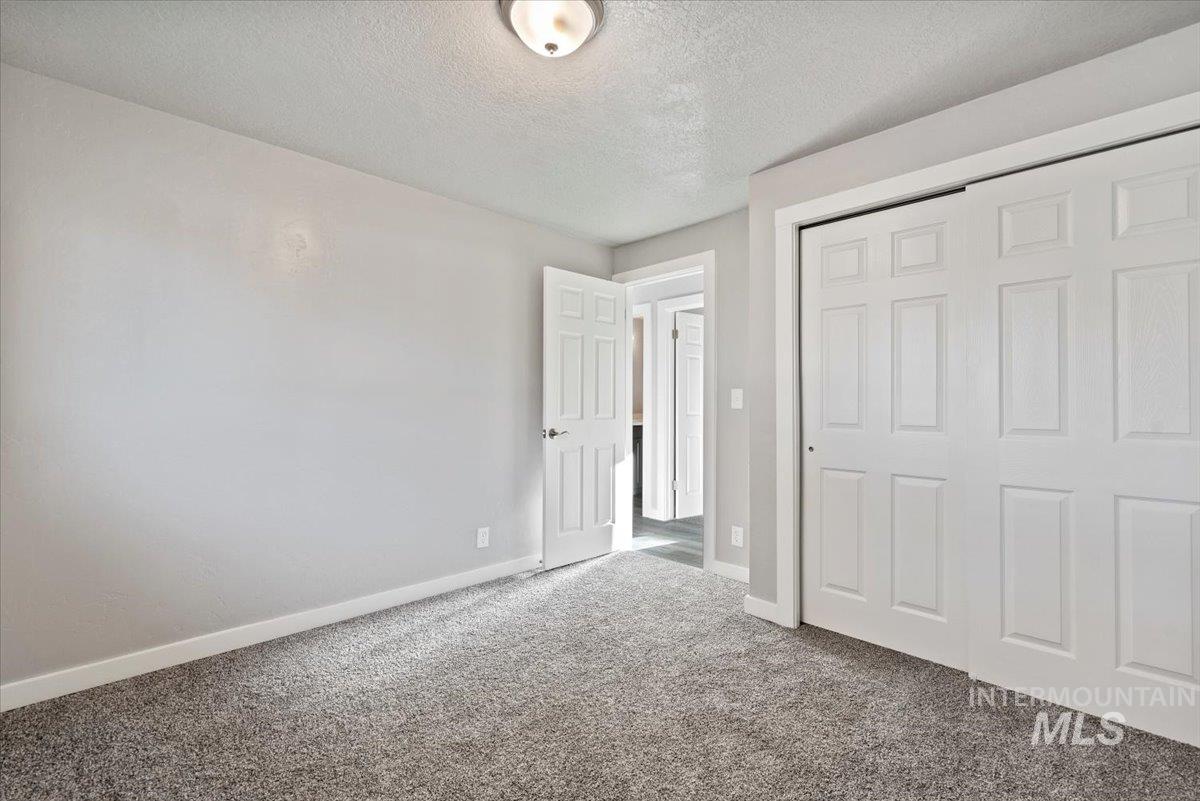 Unfurnished bedroom with a textured ceiling, a closet, and carpet flooring
