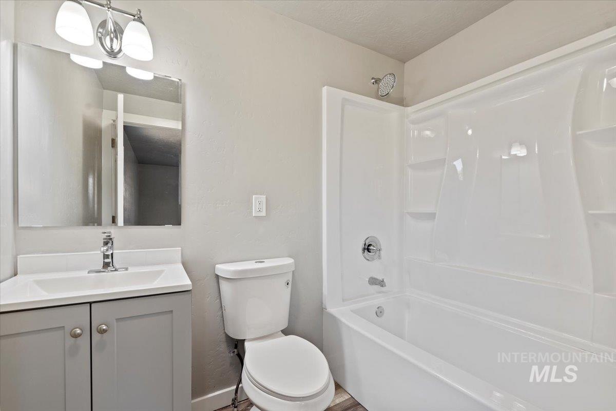 Bathroom featuring shower / tub combination, vanity, and a textured wall