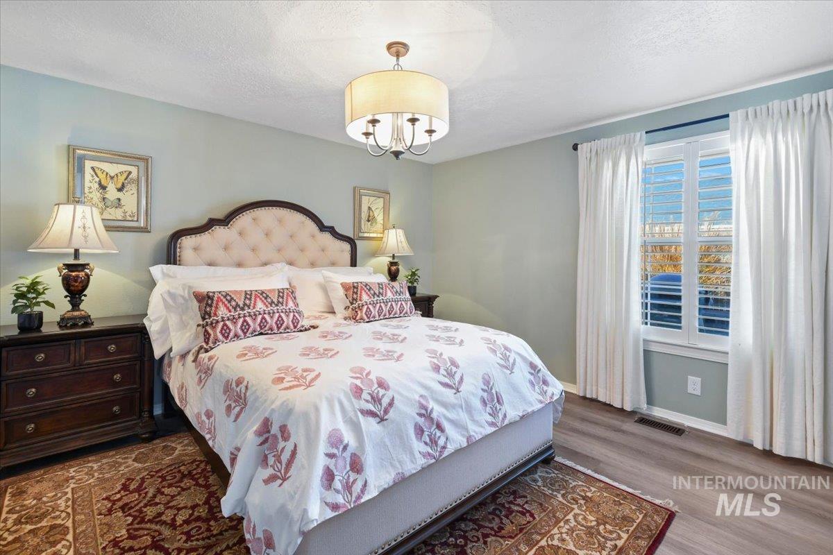 Bedroom featuring dark wood-type flooring, a textured ceiling, and a chandelier