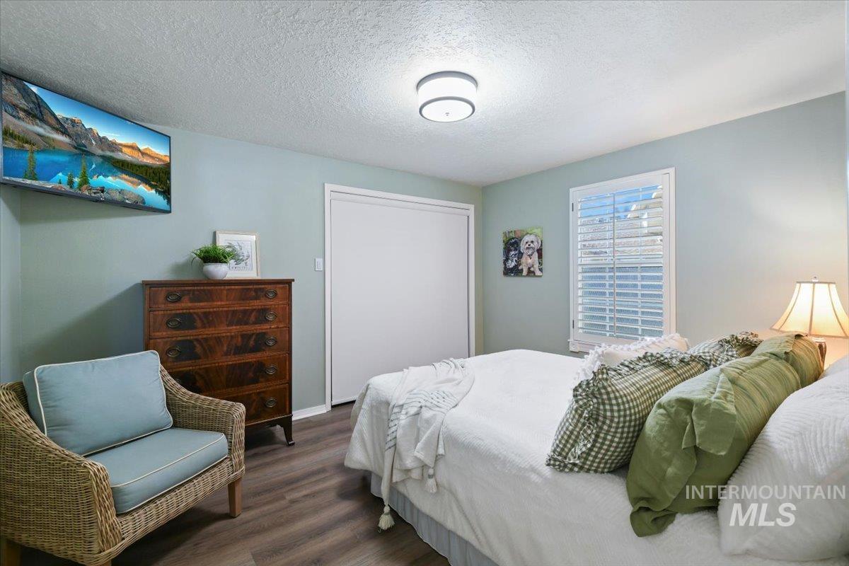 Bedroom featuring a textured ceiling, wood finished floors, and a closet