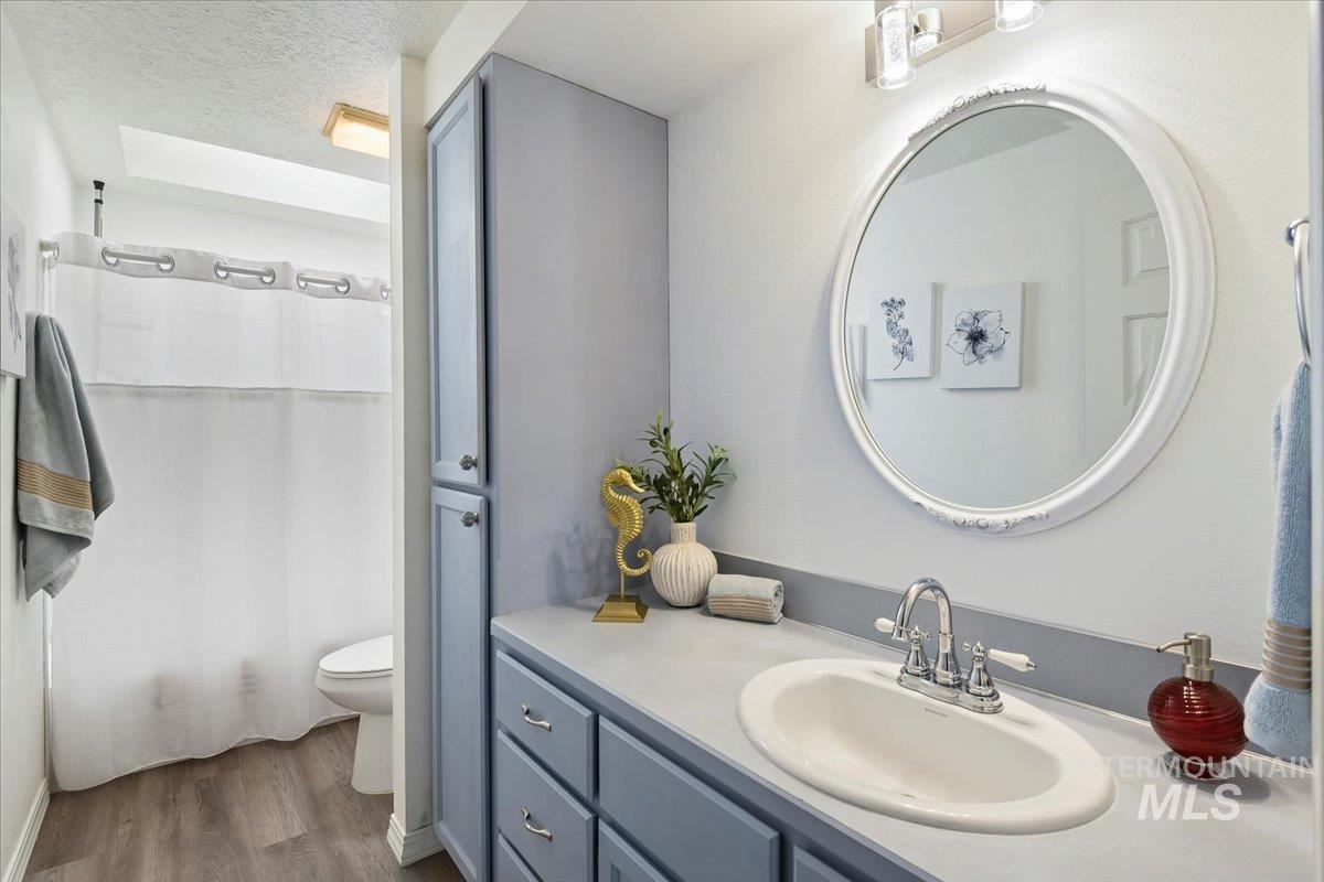 Full bathroom featuring a textured ceiling, vanity, and dark wood-style flooring