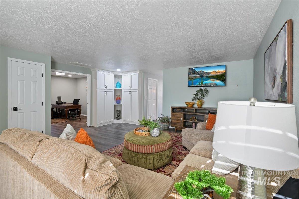 Living area with a desk, a textured ceiling, and wood finished floors