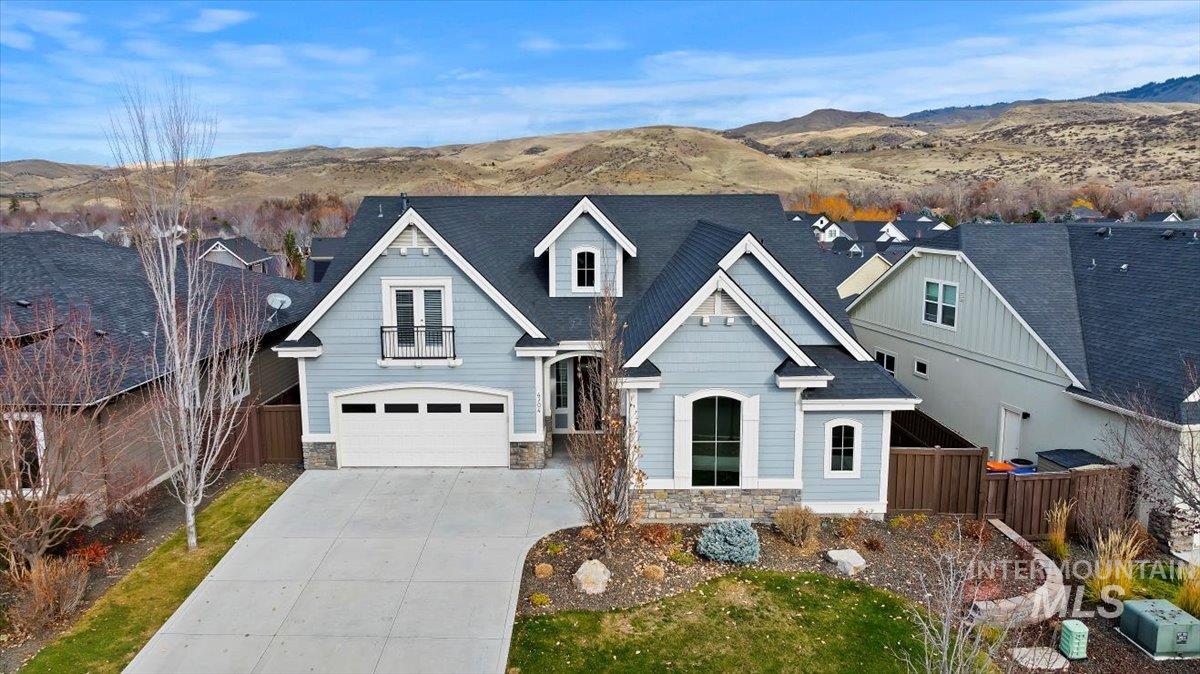 View of front facade with a mountain view, stone siding, and driveway