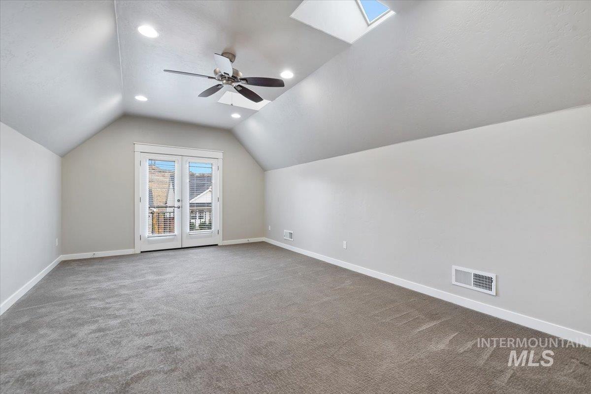 Additional living space featuring lofted ceiling, light carpet, recessed lighting, a textured ceiling, and a skylight