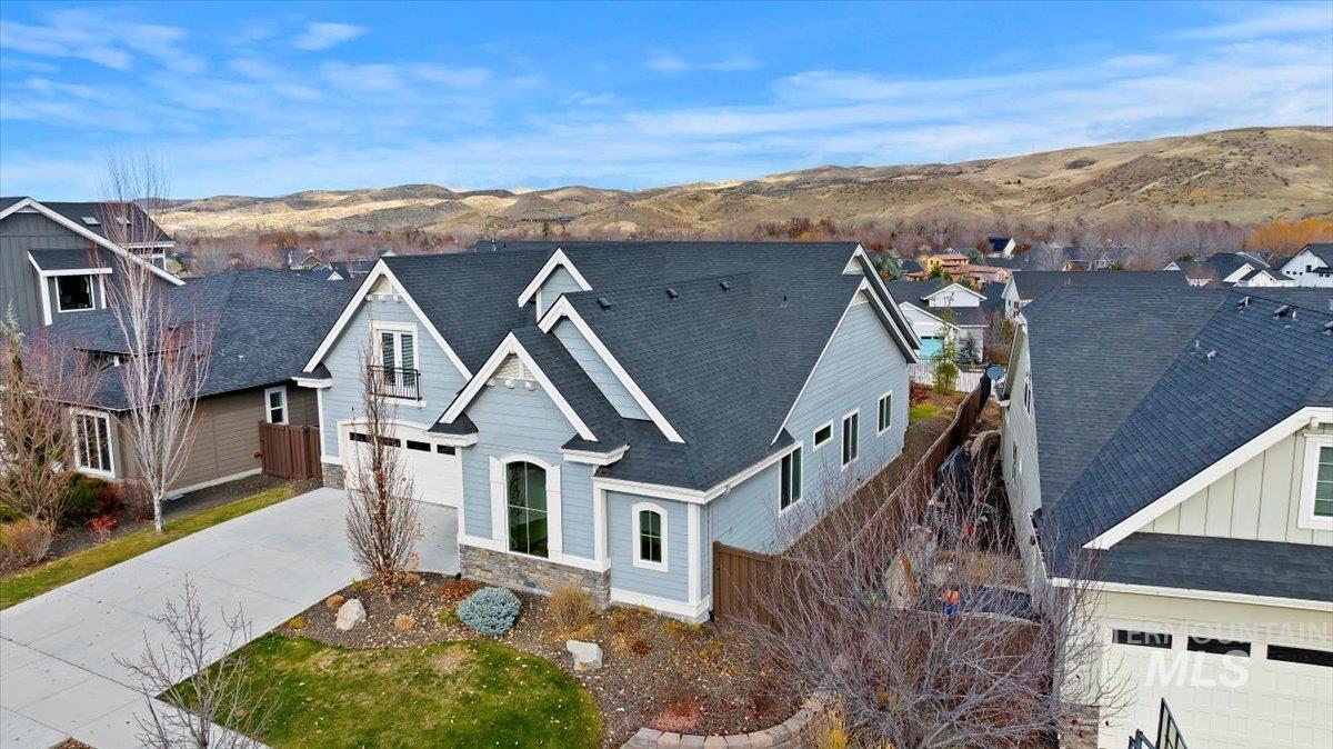 View of front of home with roof with shingles, driveway, a mountain view, and stone siding