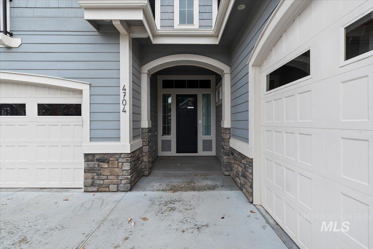 Property entrance with a garage and stone siding