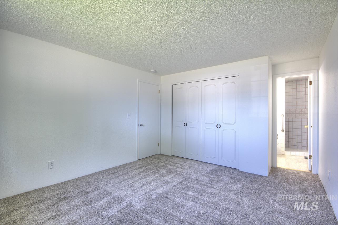 Unfurnished bedroom featuring a textured ceiling, carpet flooring, and a closet