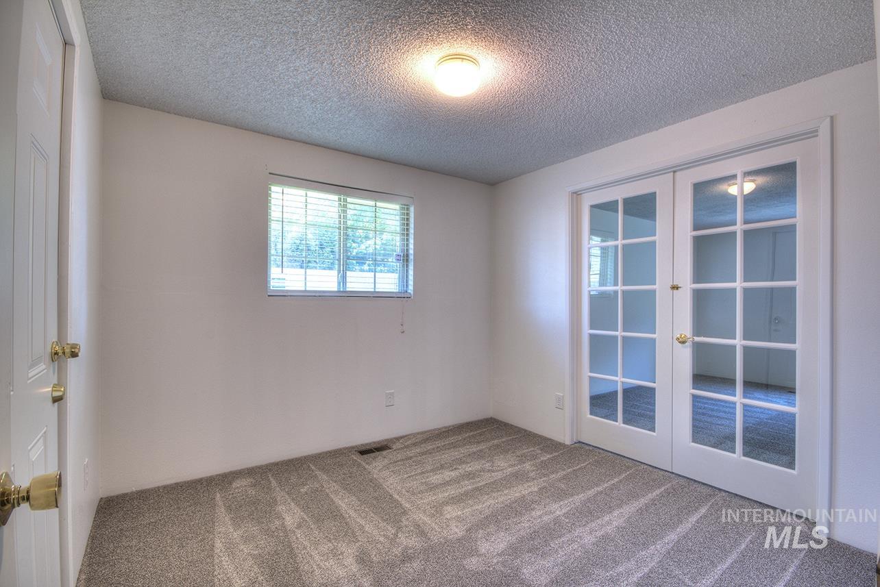 Unfurnished room with french doors, a textured ceiling, and carpet floors