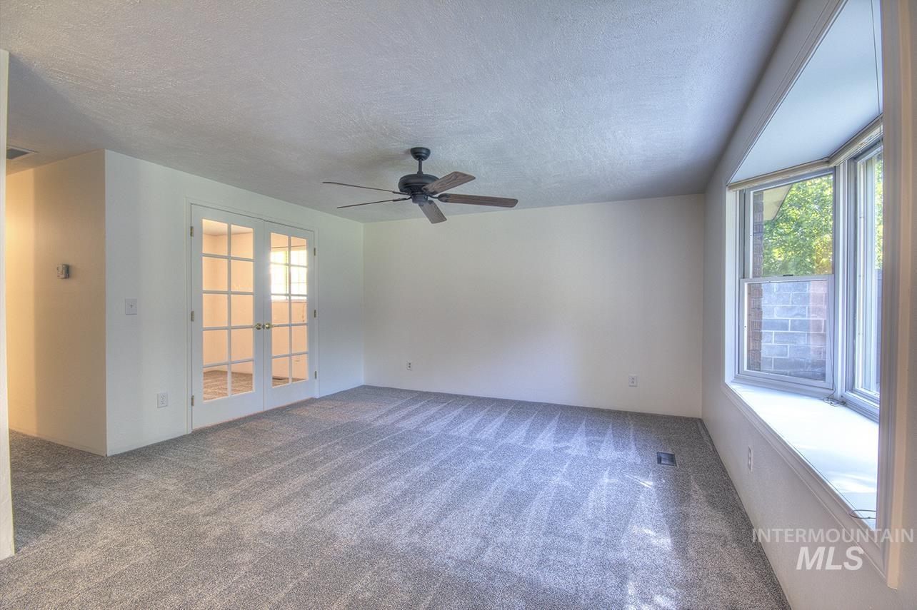 Unfurnished room with french doors, a textured ceiling, dark carpet, and ceiling fan