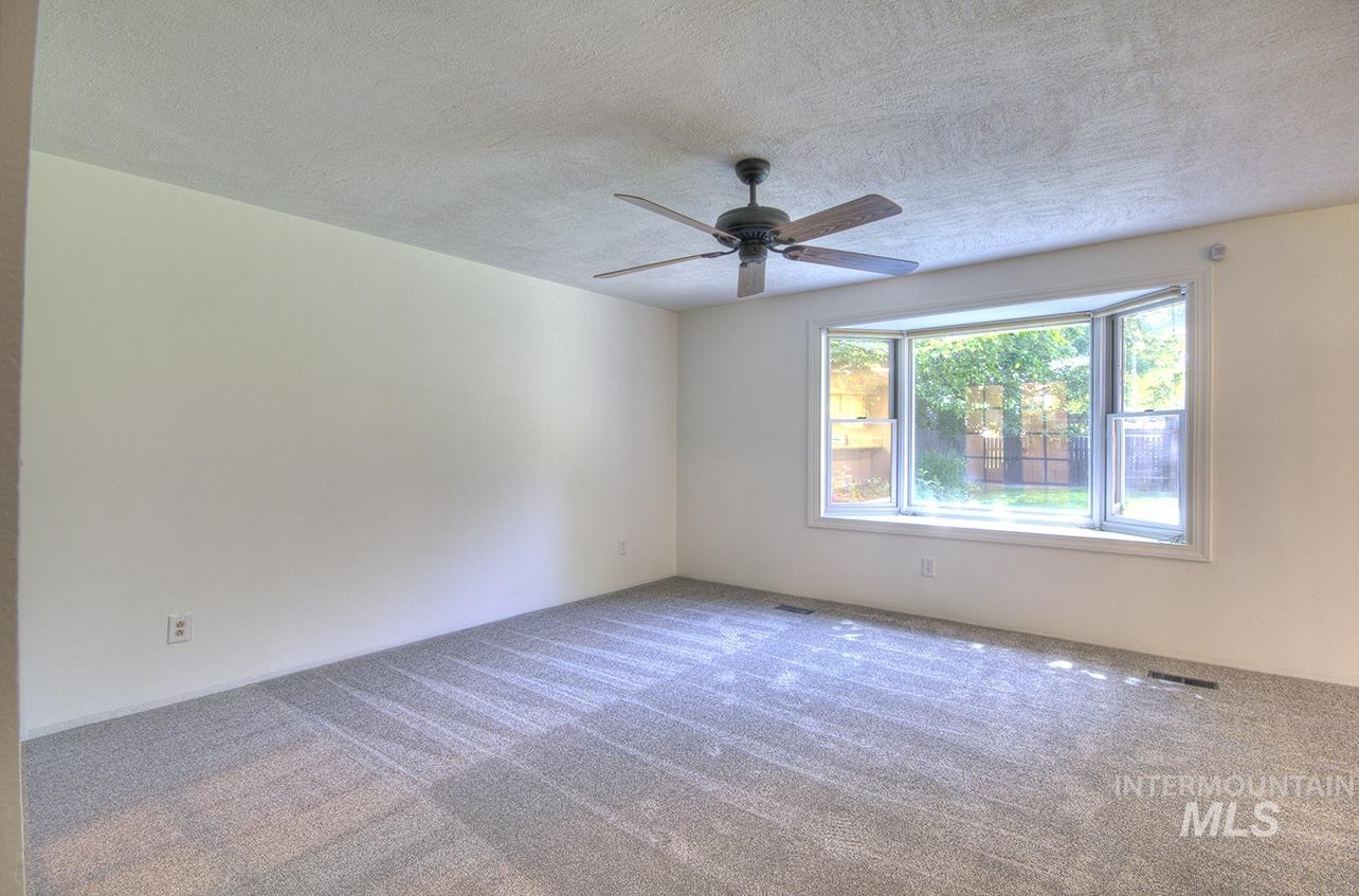 Empty room featuring carpet floors, a textured ceiling, and ceiling fan