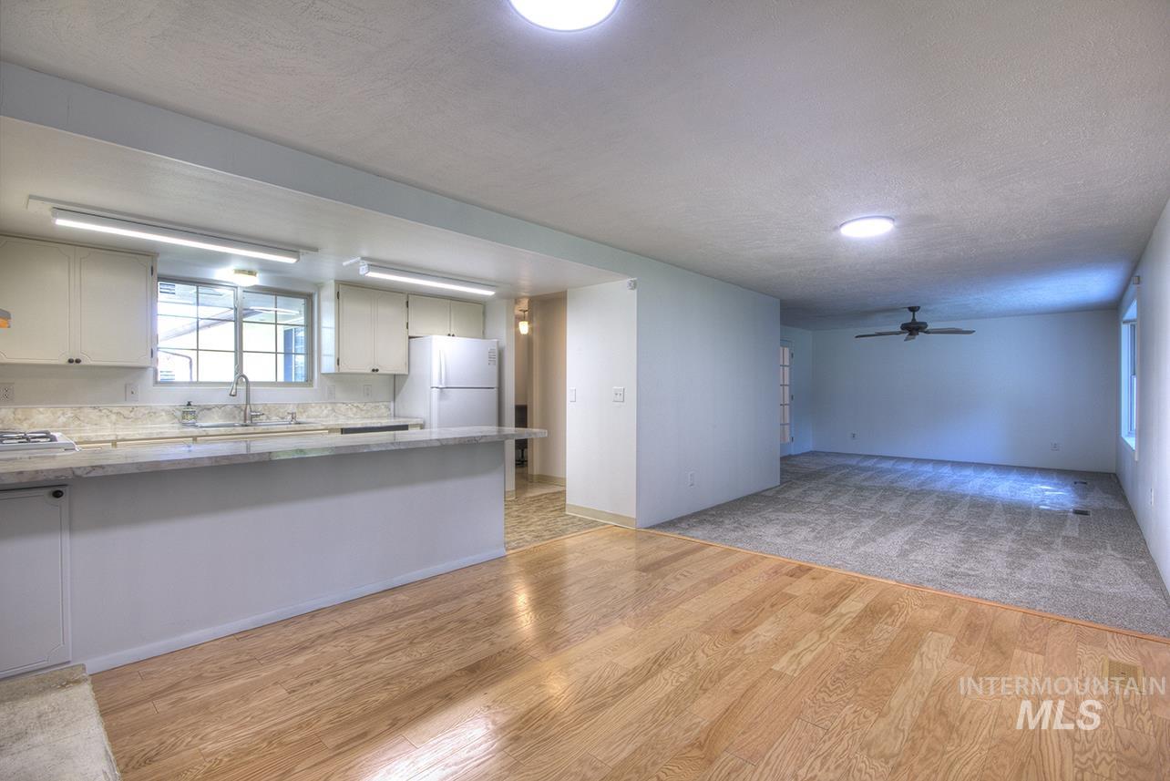 Kitchen featuring a ceiling fan, white cabinets, freestanding refrigerator, light wood-style flooring, and a textured ceiling