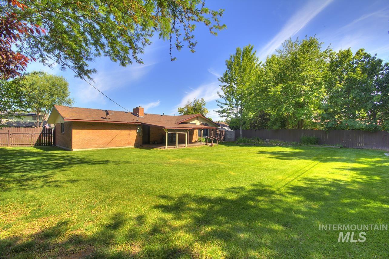 Rear view of house featuring a fenced backyard, a patio, a chimney, and brick siding