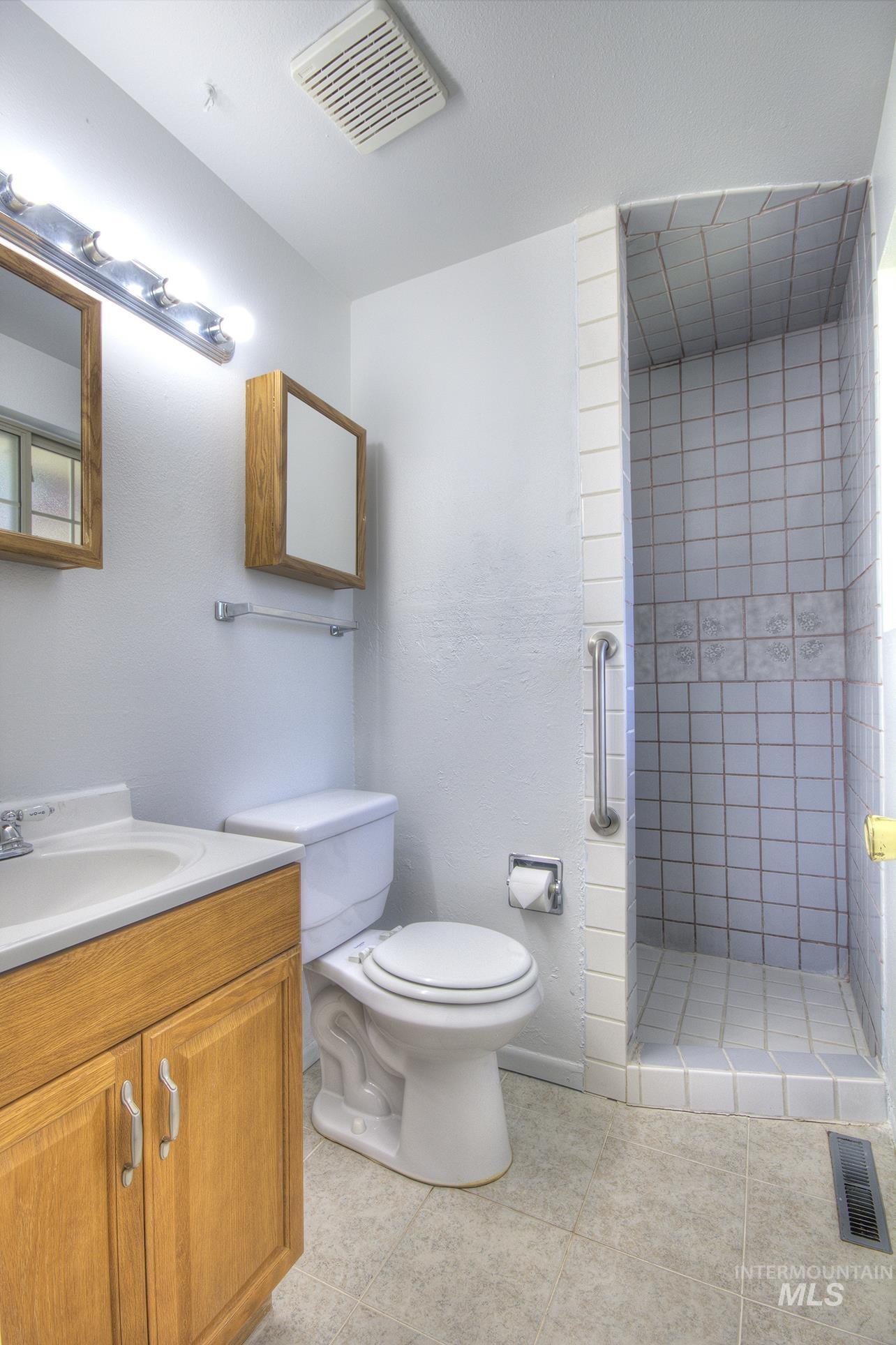 Full bath with vanity, a stall shower, and light tile patterned floors