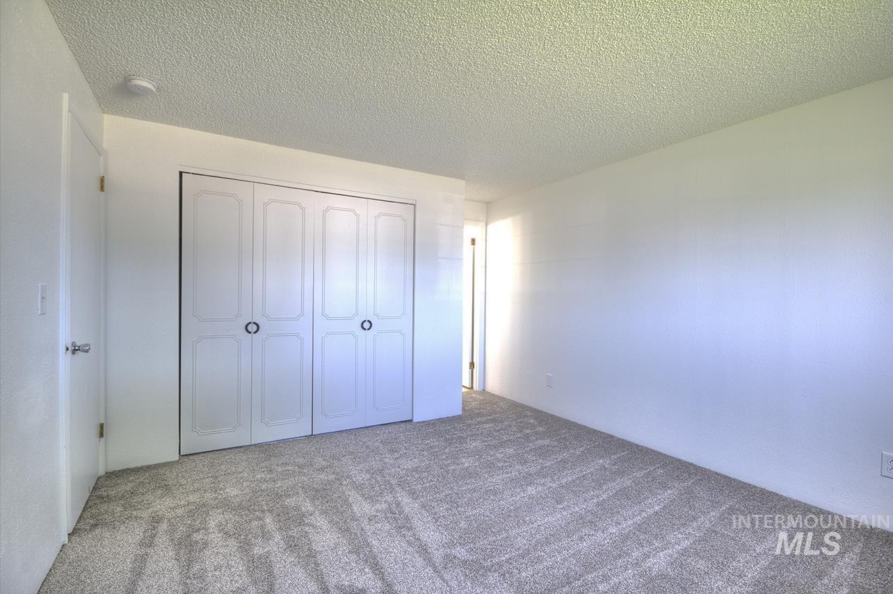 Unfurnished bedroom featuring a textured ceiling, carpet, and a closet