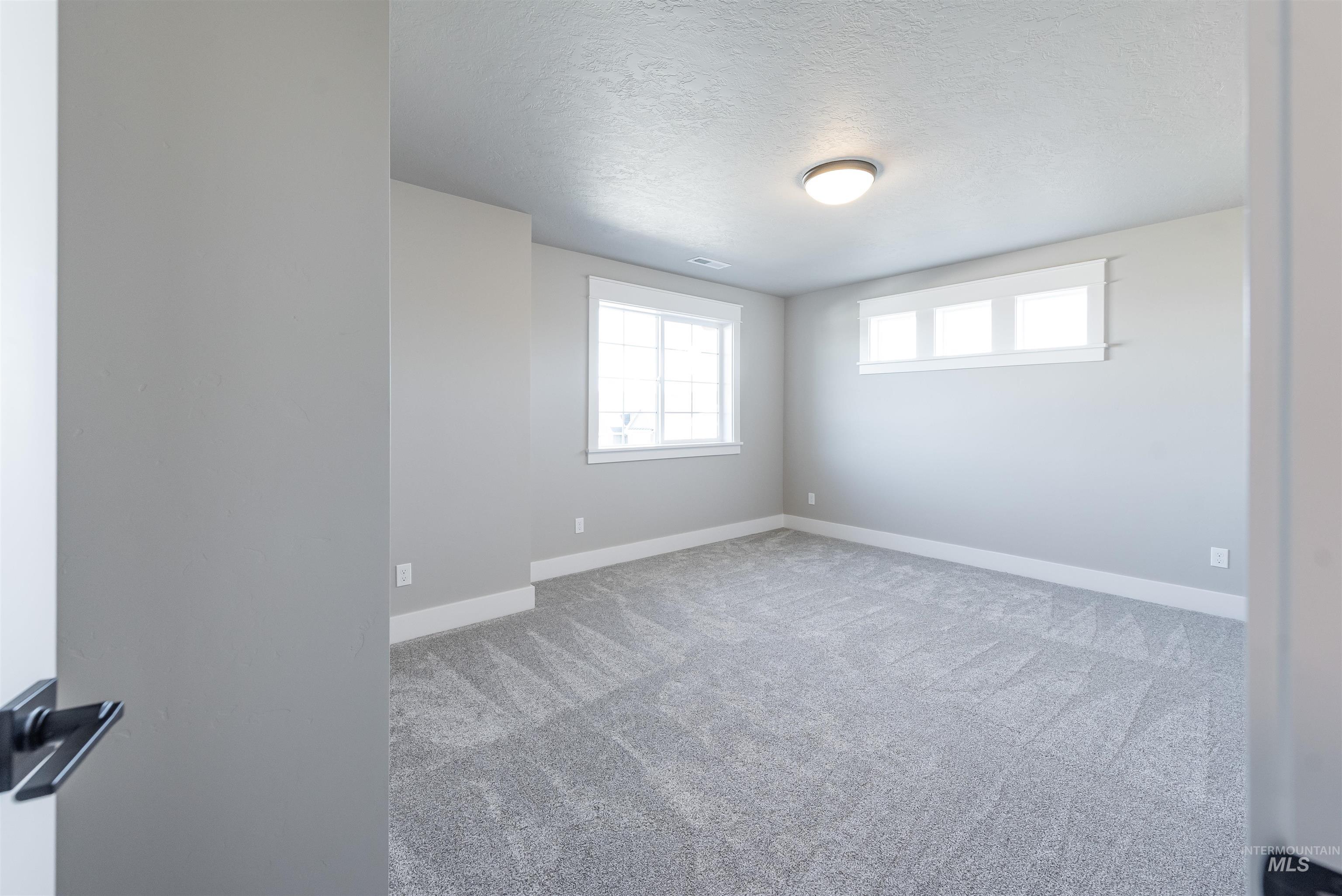 Unfurnished room with a textured ceiling and light carpet