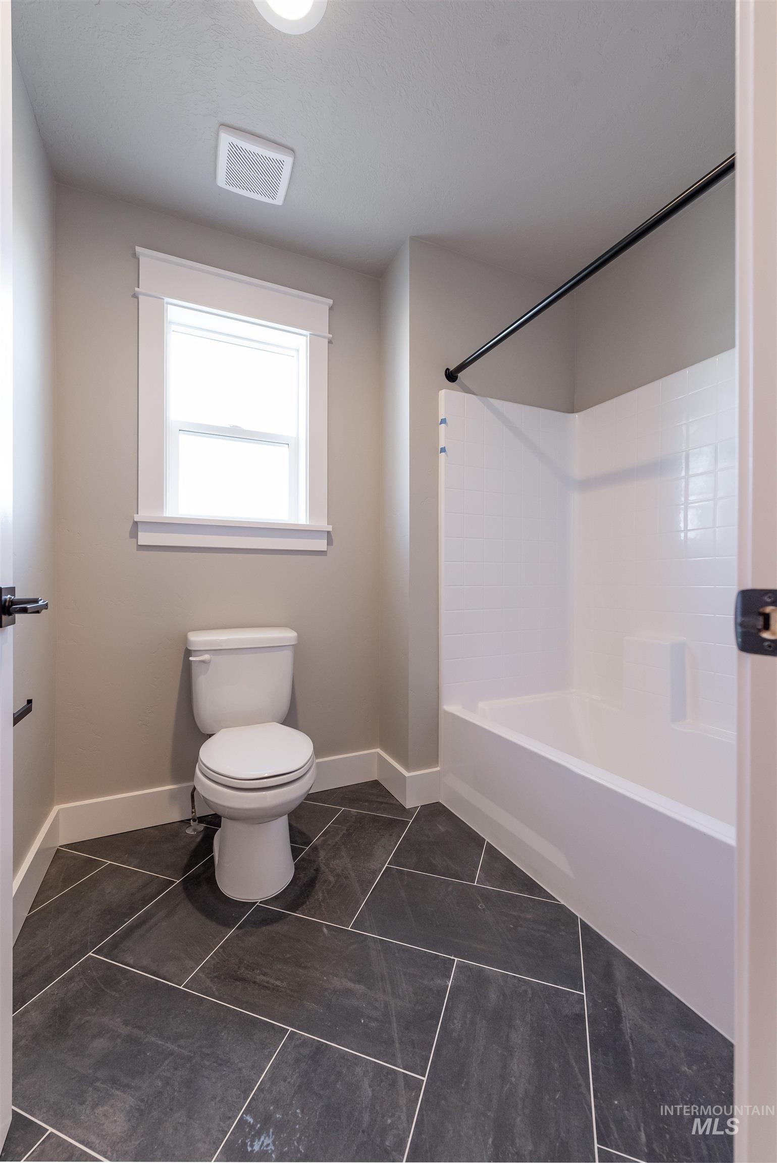 Bathroom featuring shower / bath combination and dark tile patterned floors