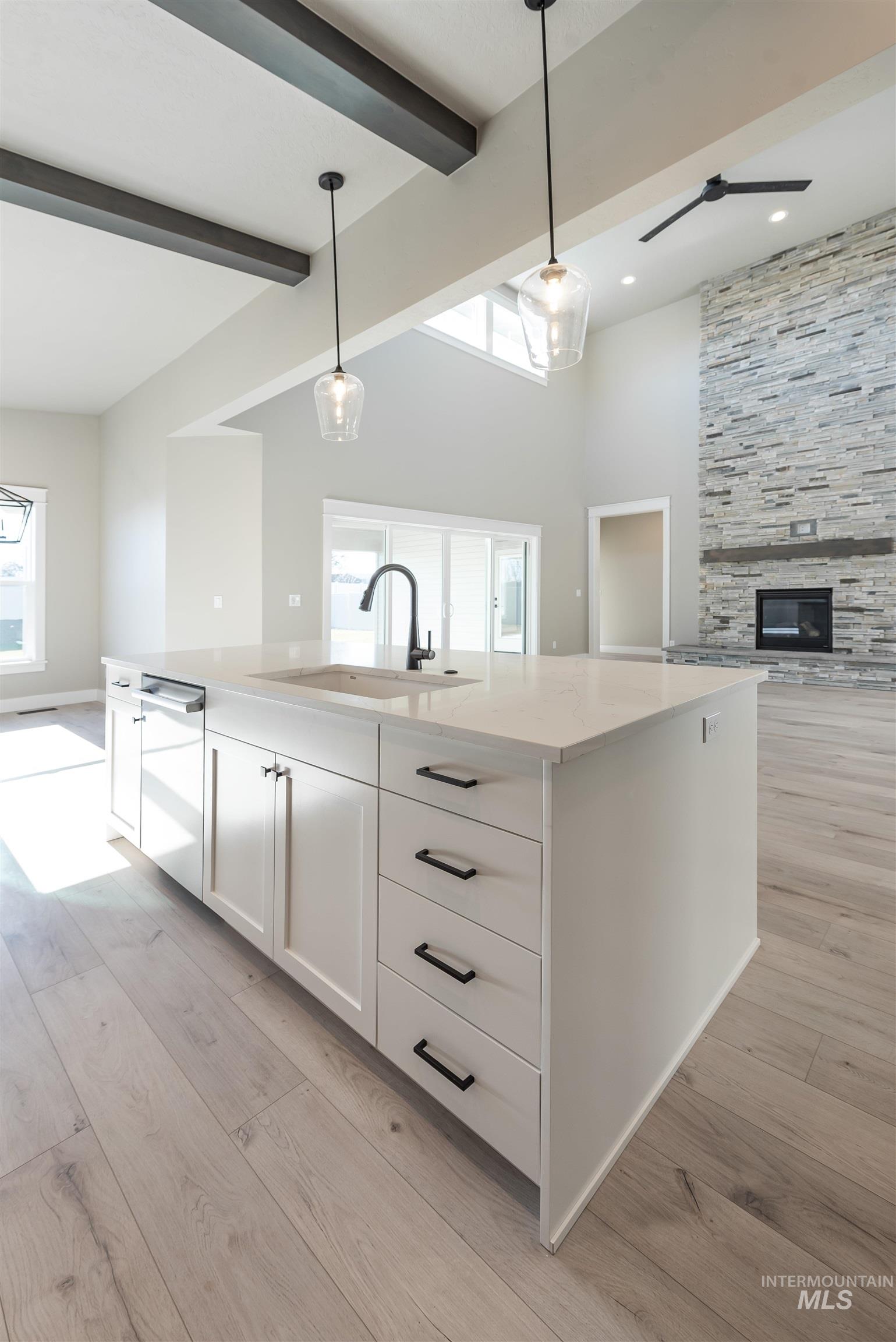 Kitchen featuring white cabinets, a center island with sink, open floor plan, hanging light fixtures, and a high ceiling