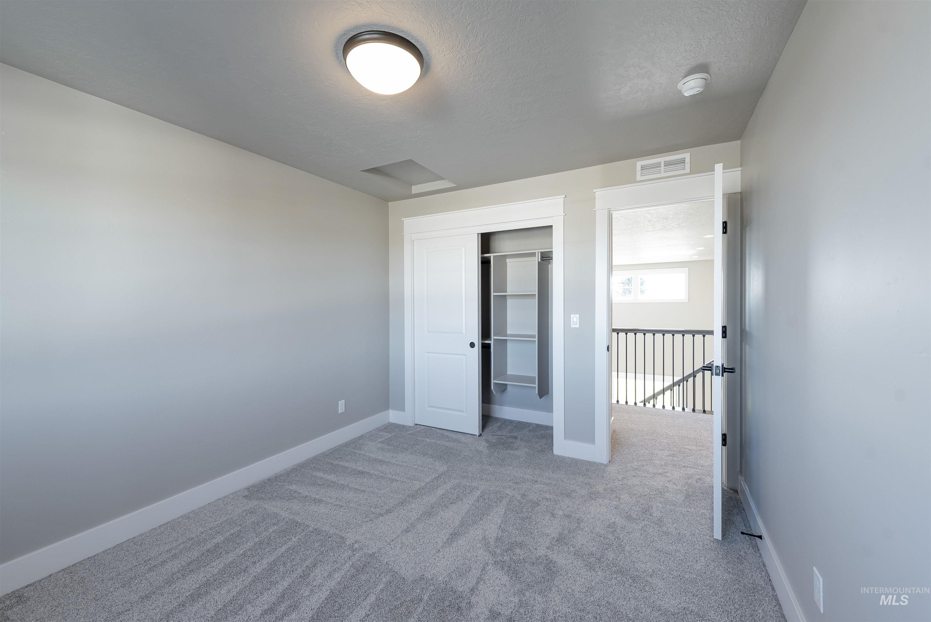 Unfurnished bedroom featuring light colored carpet, a closet, and a textured ceiling