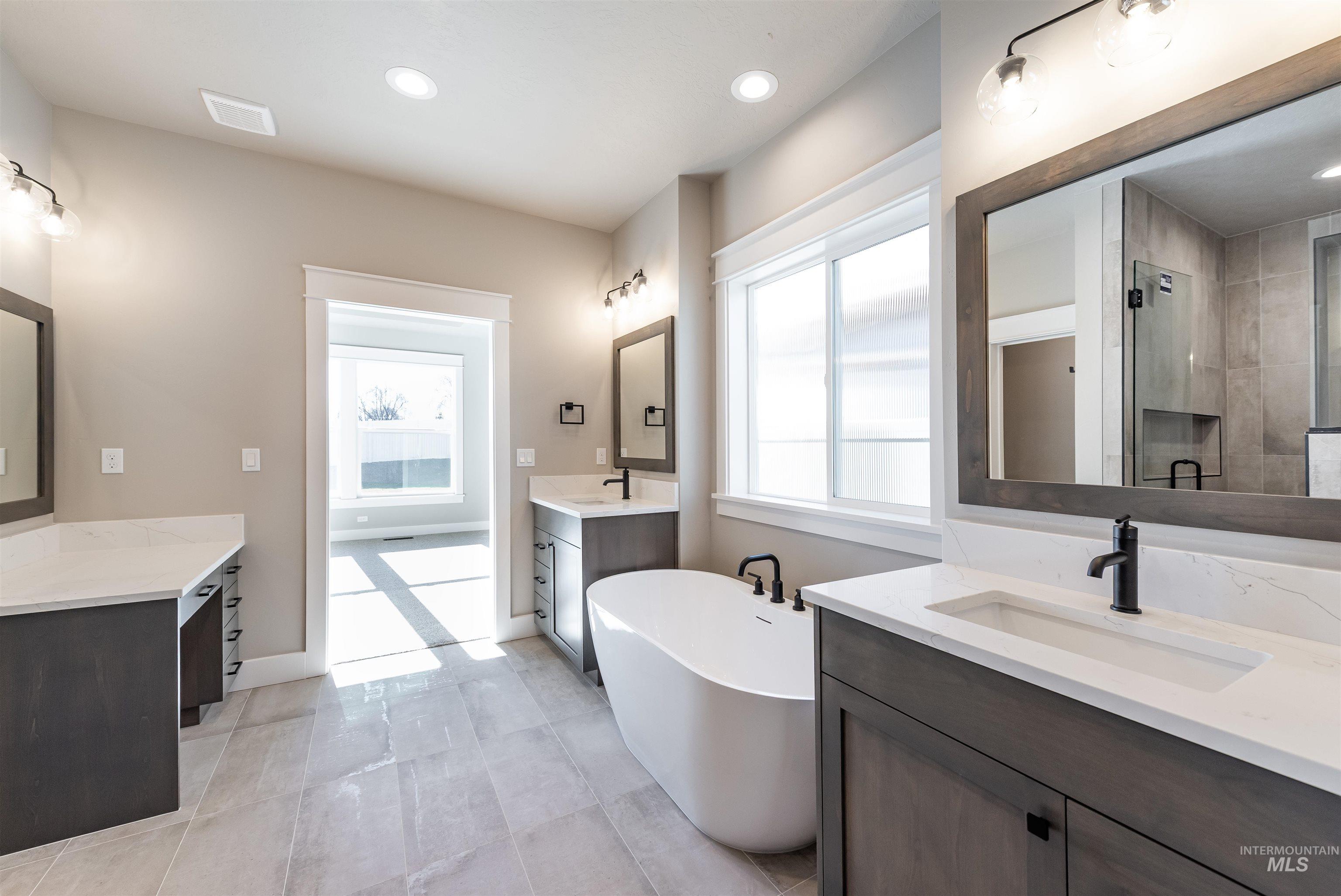 Full bathroom with a freestanding tub, two vanities, healthy amount of natural light, a stall shower, and recessed lighting