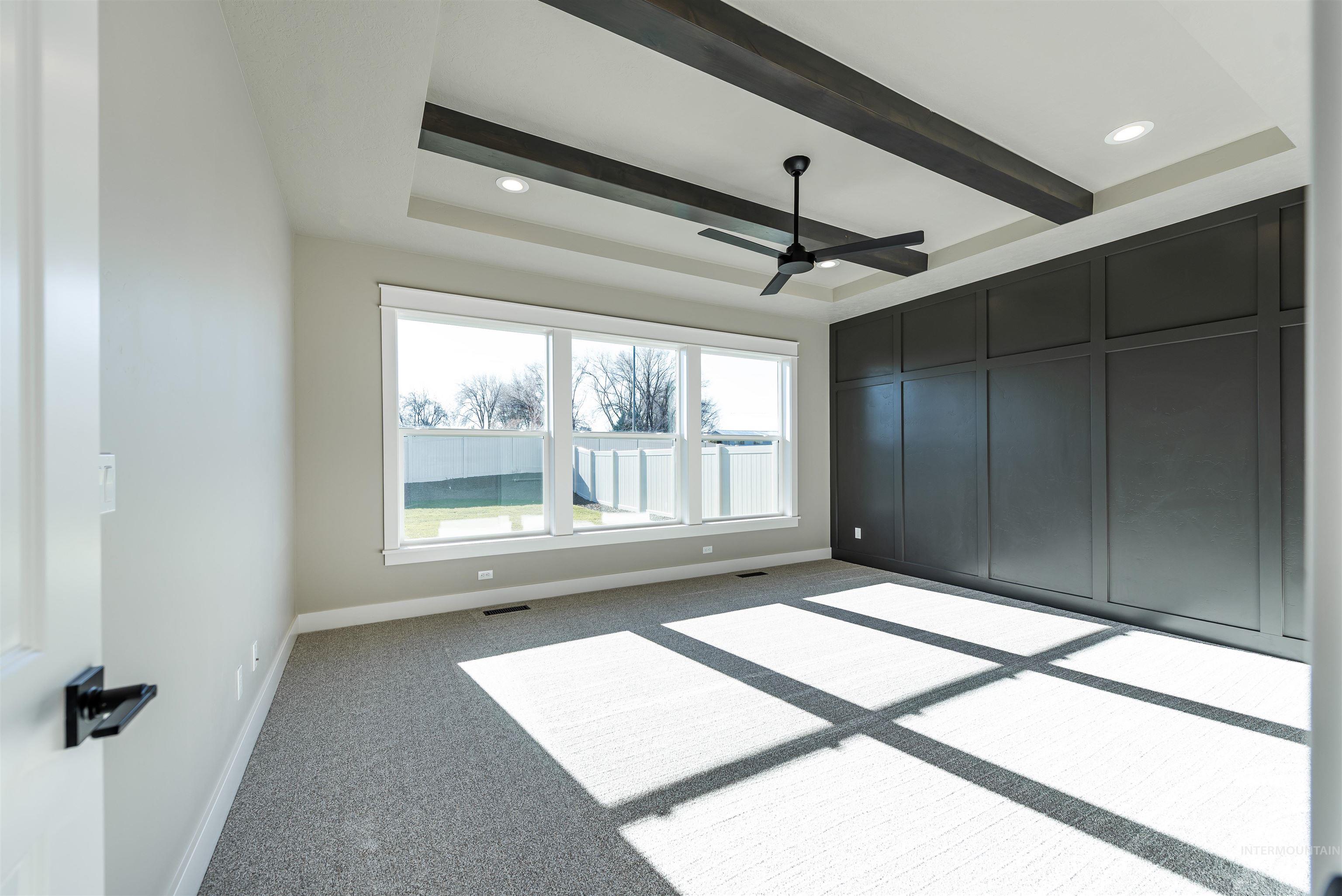 Unfurnished bedroom with carpet flooring, ceiling fan, and beam ceiling