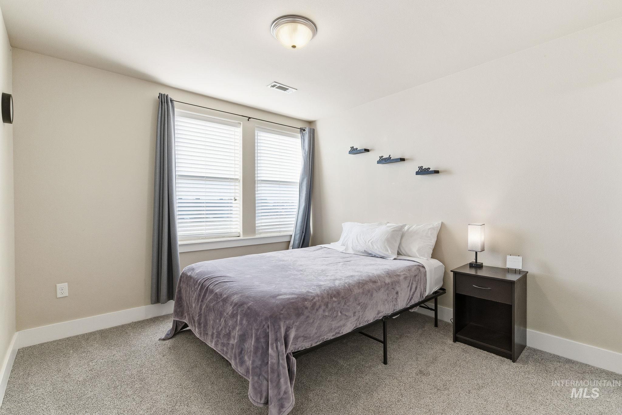 Bedroom featuring light carpet and baseboards