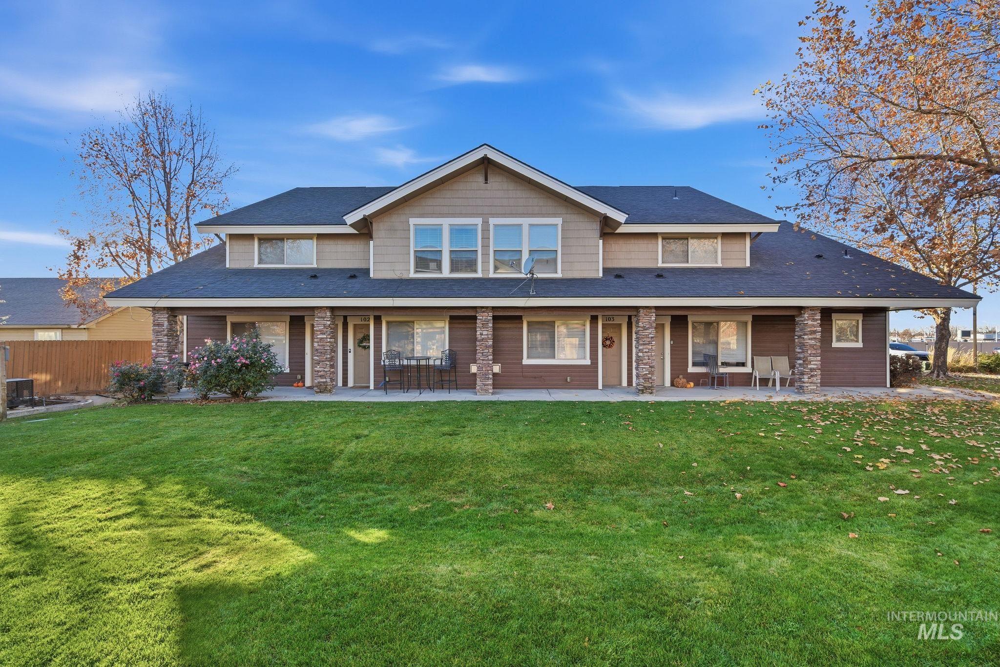 Rear view of house with a lawn, stone siding, and a shingled roof