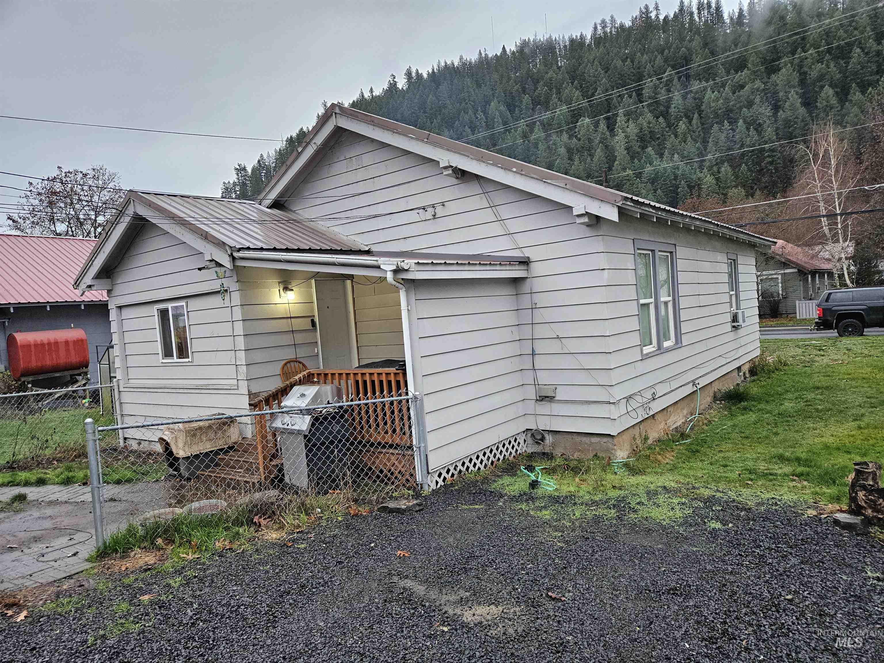 Bungalow-style house with a metal roof, heating fuel, a forest view, and a gate