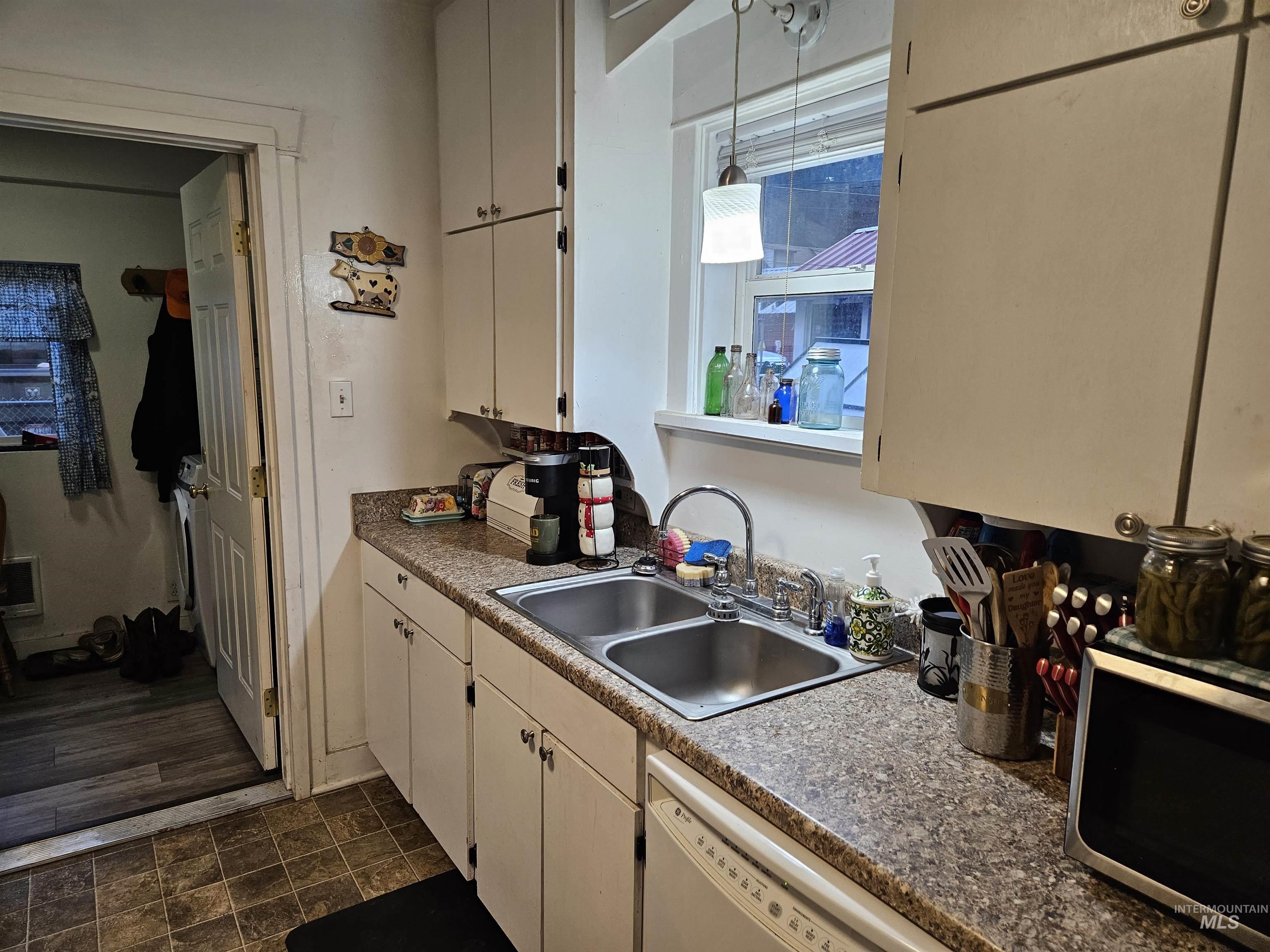 Kitchen with stainless steel microwave, white dishwasher, and pendant lighting