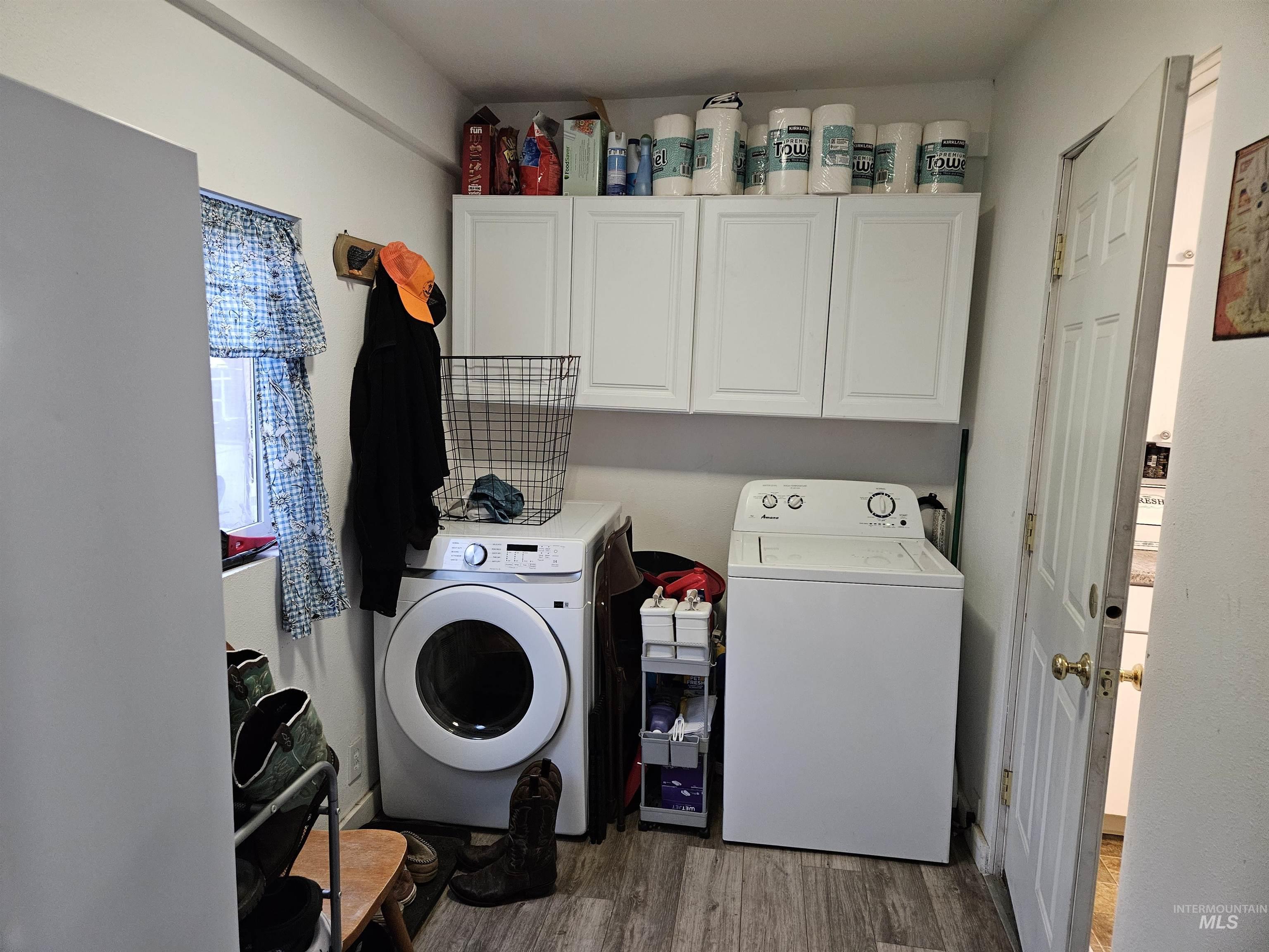 Laundry room with cabinet space, washing machine and dryer, and wood finished floors