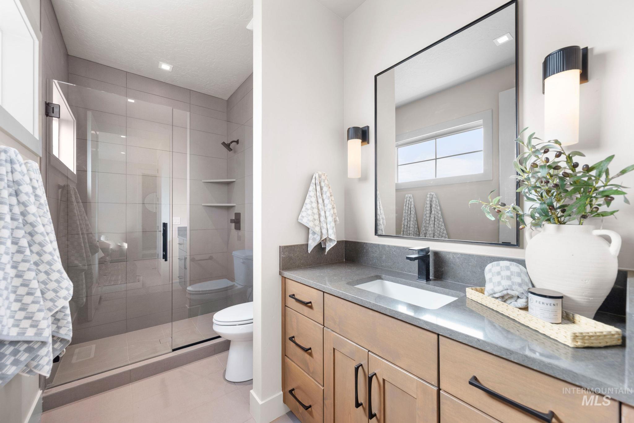 Full bath featuring vanity, a stall shower, and light tile patterned floors