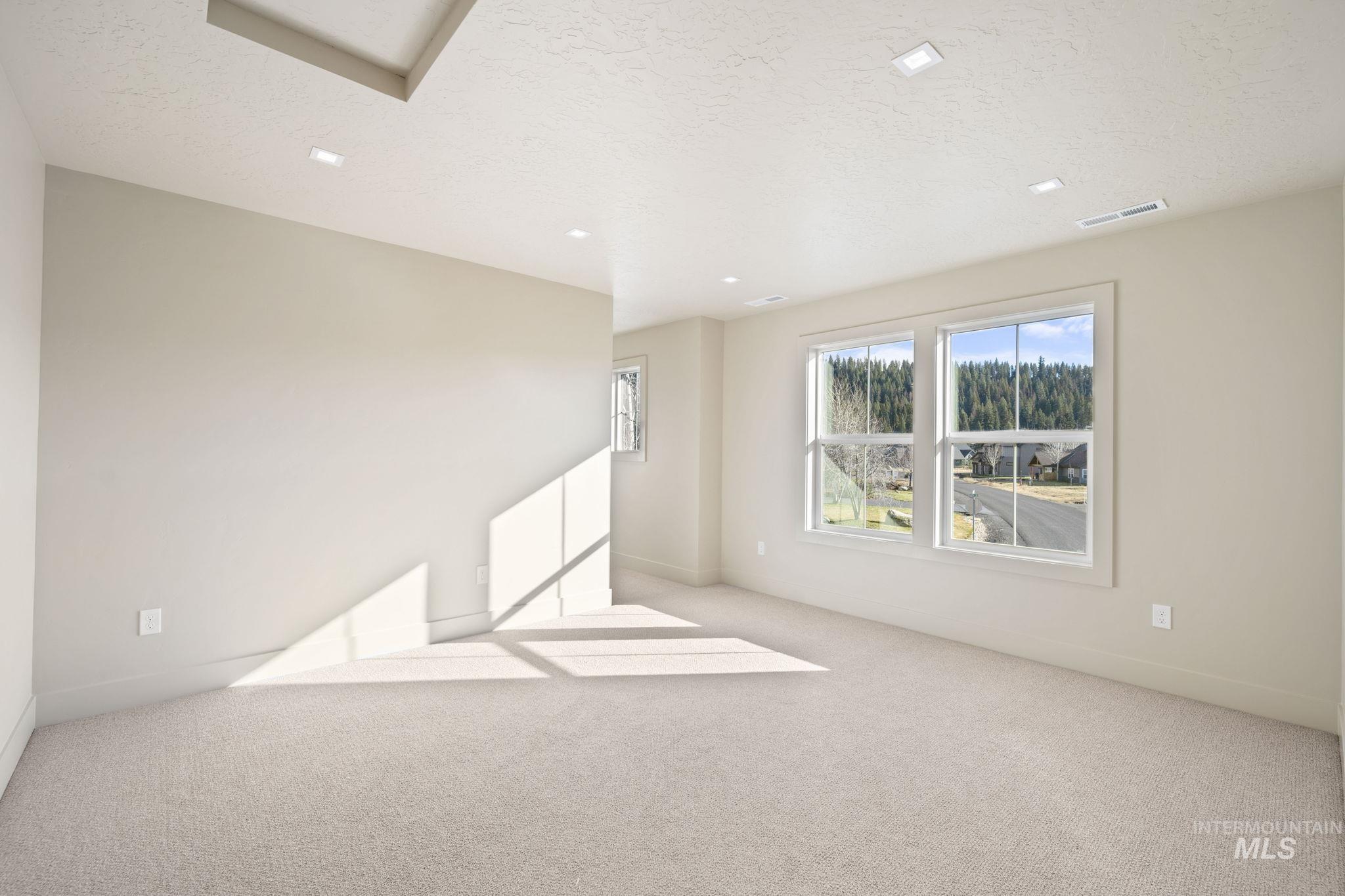 Carpeted empty room featuring a textured ceiling and baseboards