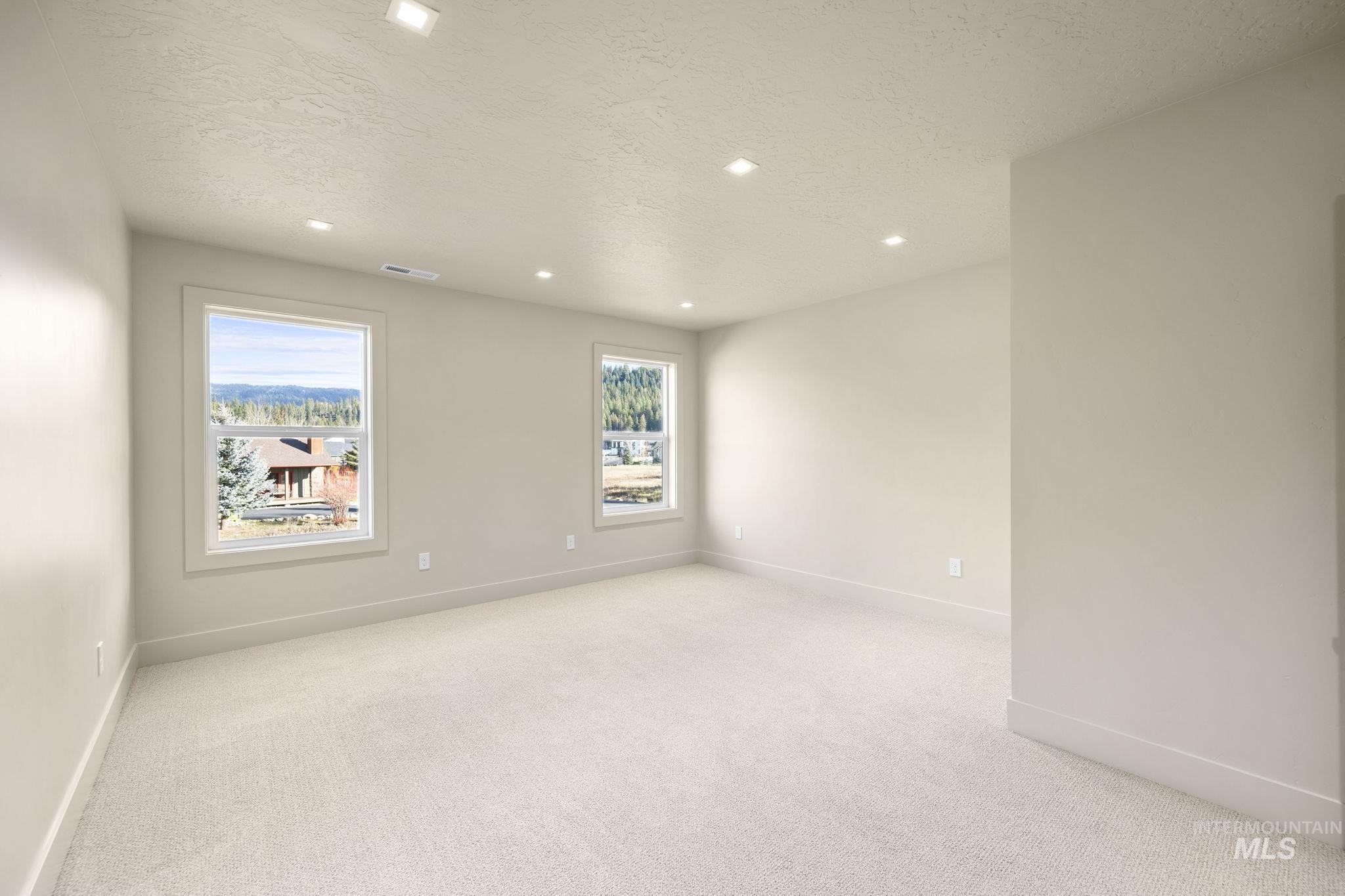 Empty room with light colored carpet, a textured ceiling, and recessed lighting