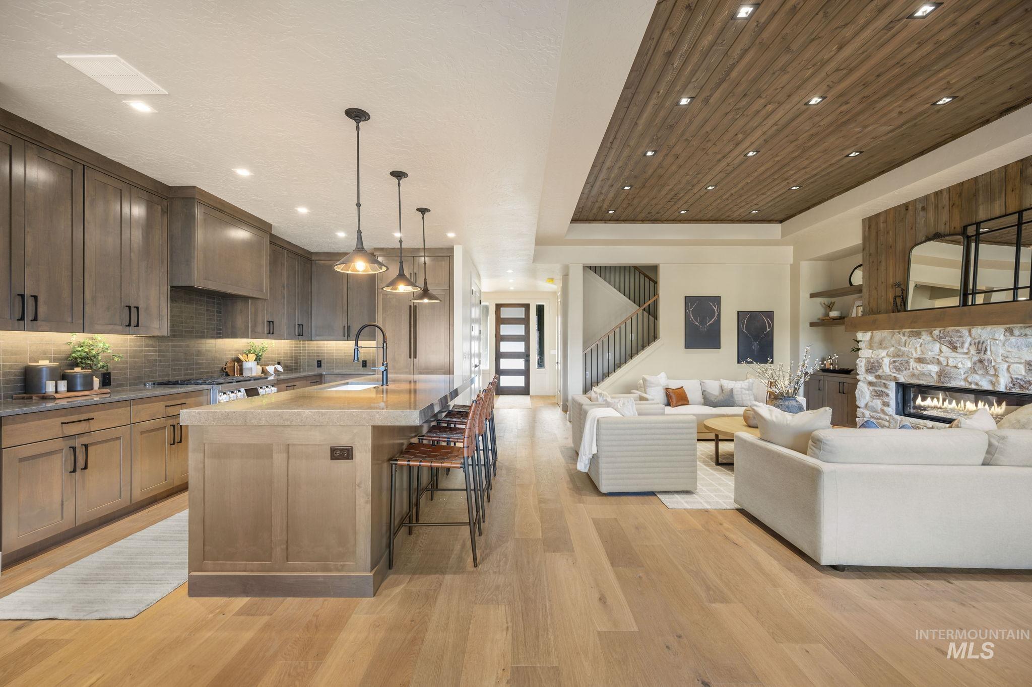 Kitchen featuring open floor plan, hanging light fixtures, a kitchen island with sink, a breakfast bar area, and light wood-style flooring