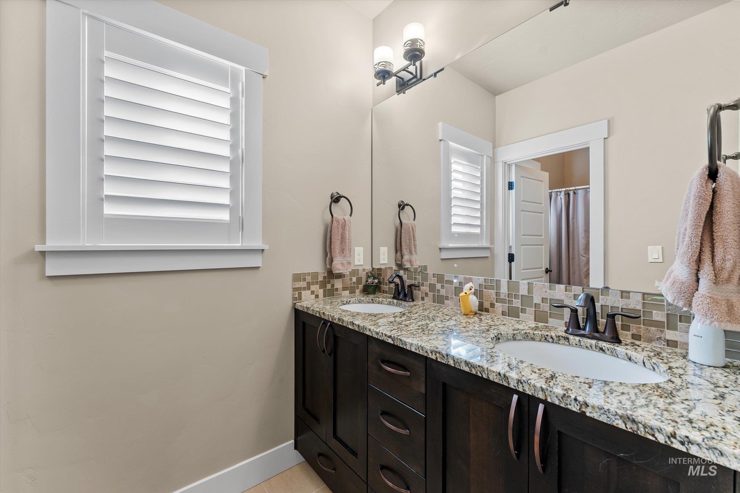 Full bathroom featuring decorative backsplash, double vanity, and curtained shower