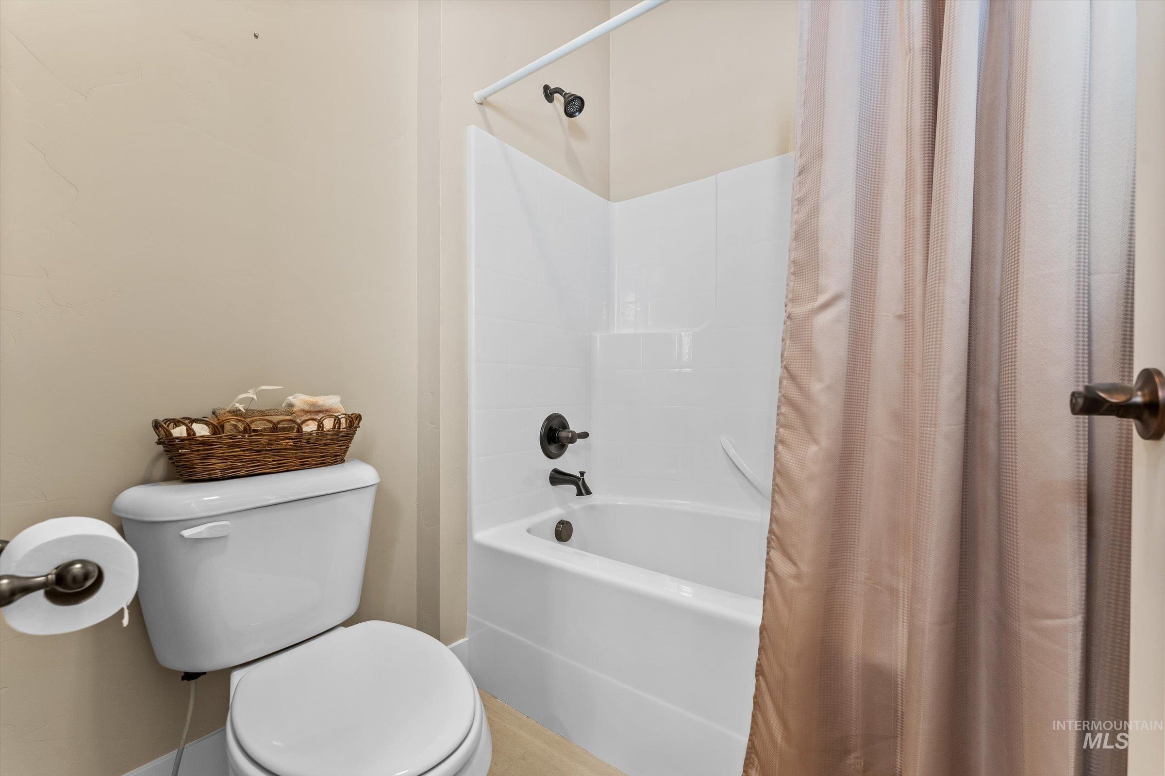 Bathroom with shower / bathtub combination with curtain and toilet