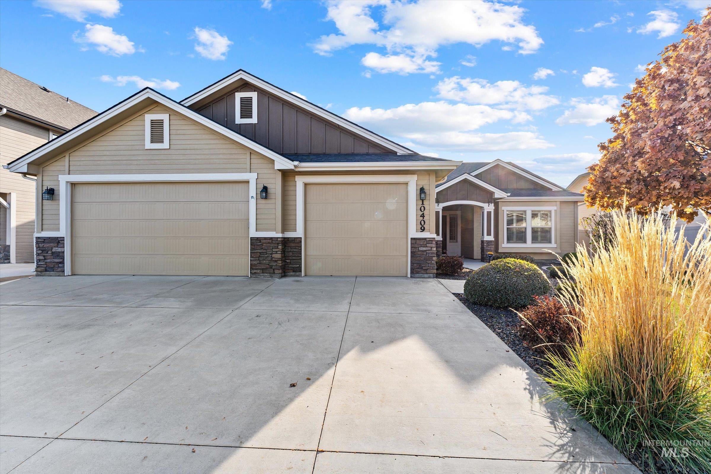 Craftsman house featuring board and batten siding, driveway, stone siding, and a garage