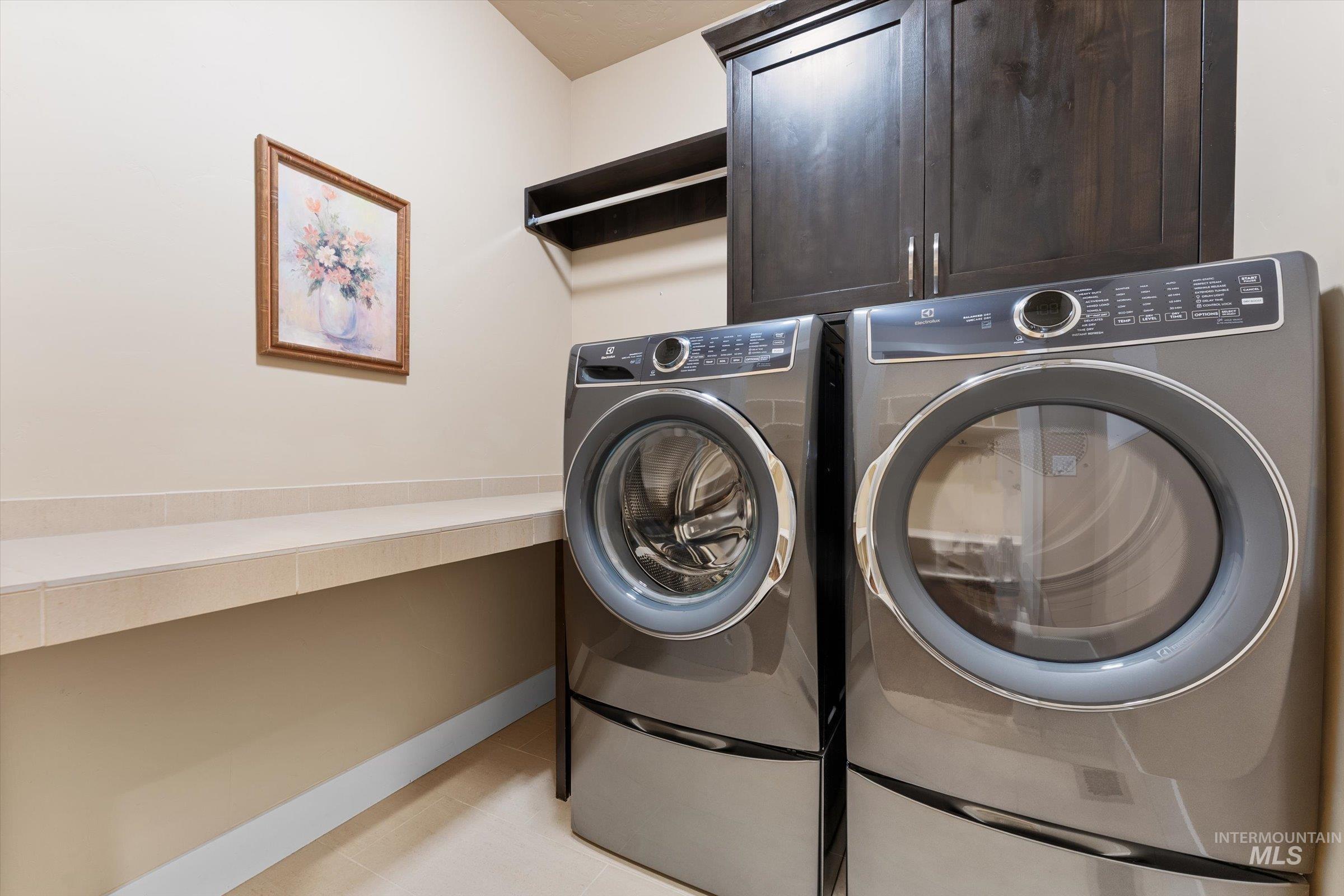 Laundry area with washer and dryer and light tile patterned floors