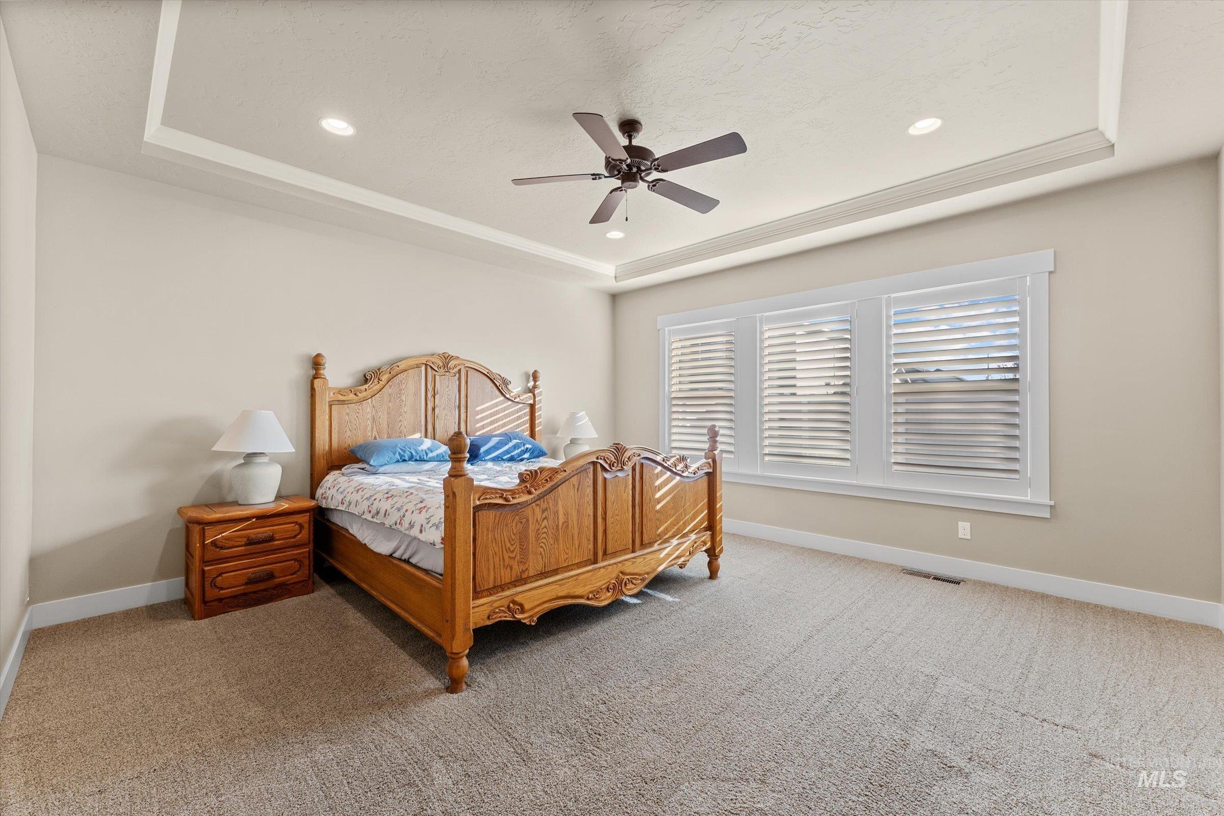 Bedroom with a tray ceiling, carpet, ceiling fan, and recessed lighting