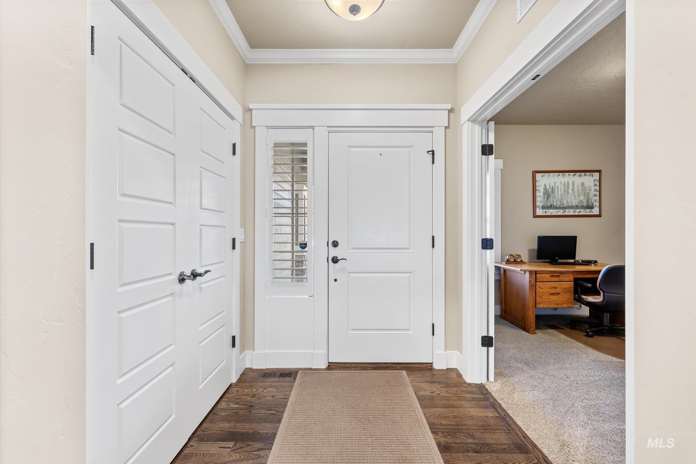 Foyer entrance with crown molding and dark wood finished floors
